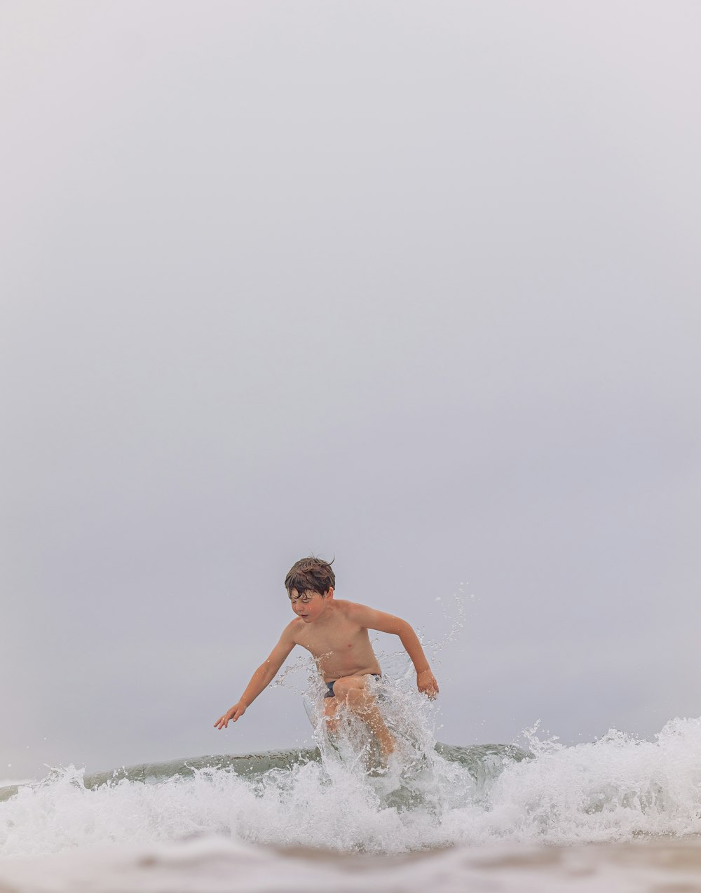 a young man riding a wave on top of a surfboard