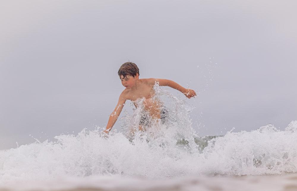 a young boy riding a wave on top of a surfboard
