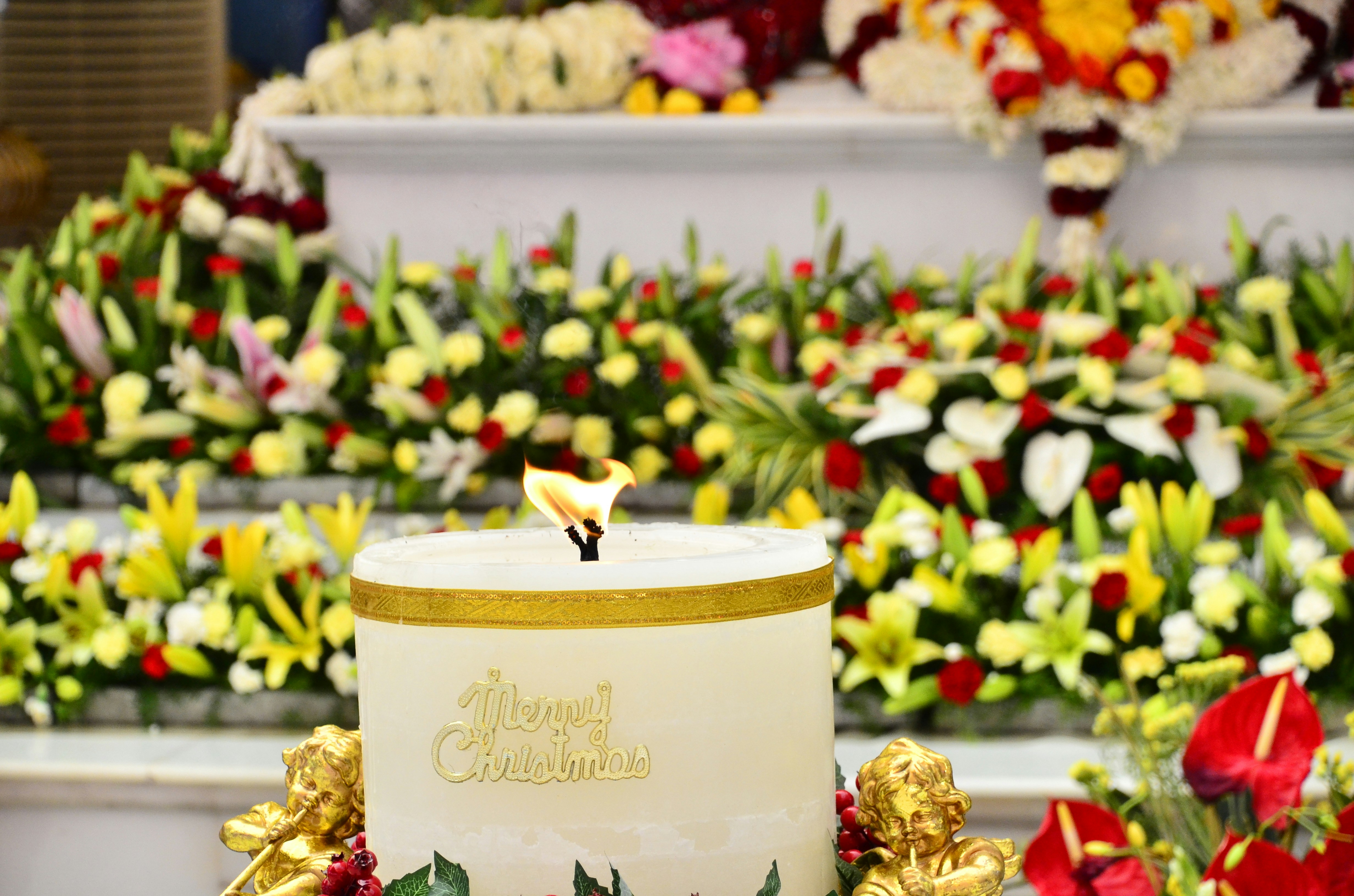a white candle with a gold top surrounded by flowers