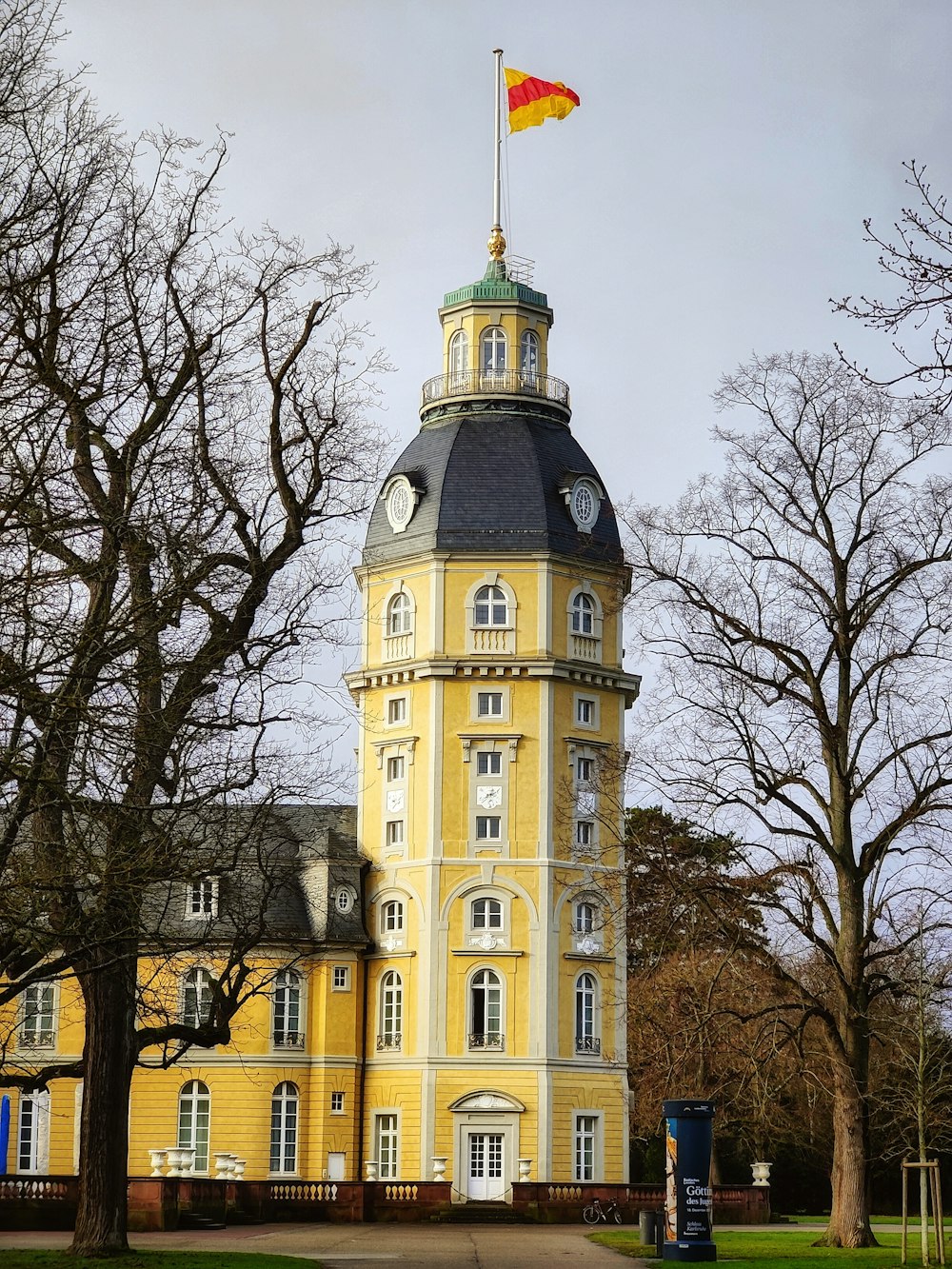 a tall yellow building with a flag on top of it