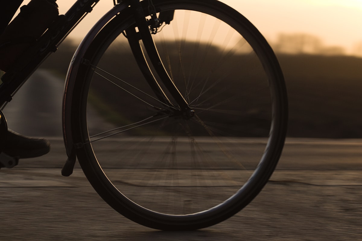 Roda de bicicleta em movimento ao entardecer, transmitindo o ritmo constante de uma pedalada em zona aeróbica