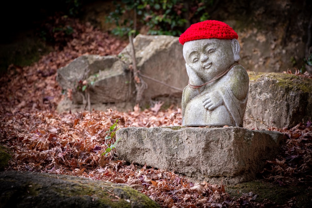 une statue en pierre avec un chapeau tricoté rouge