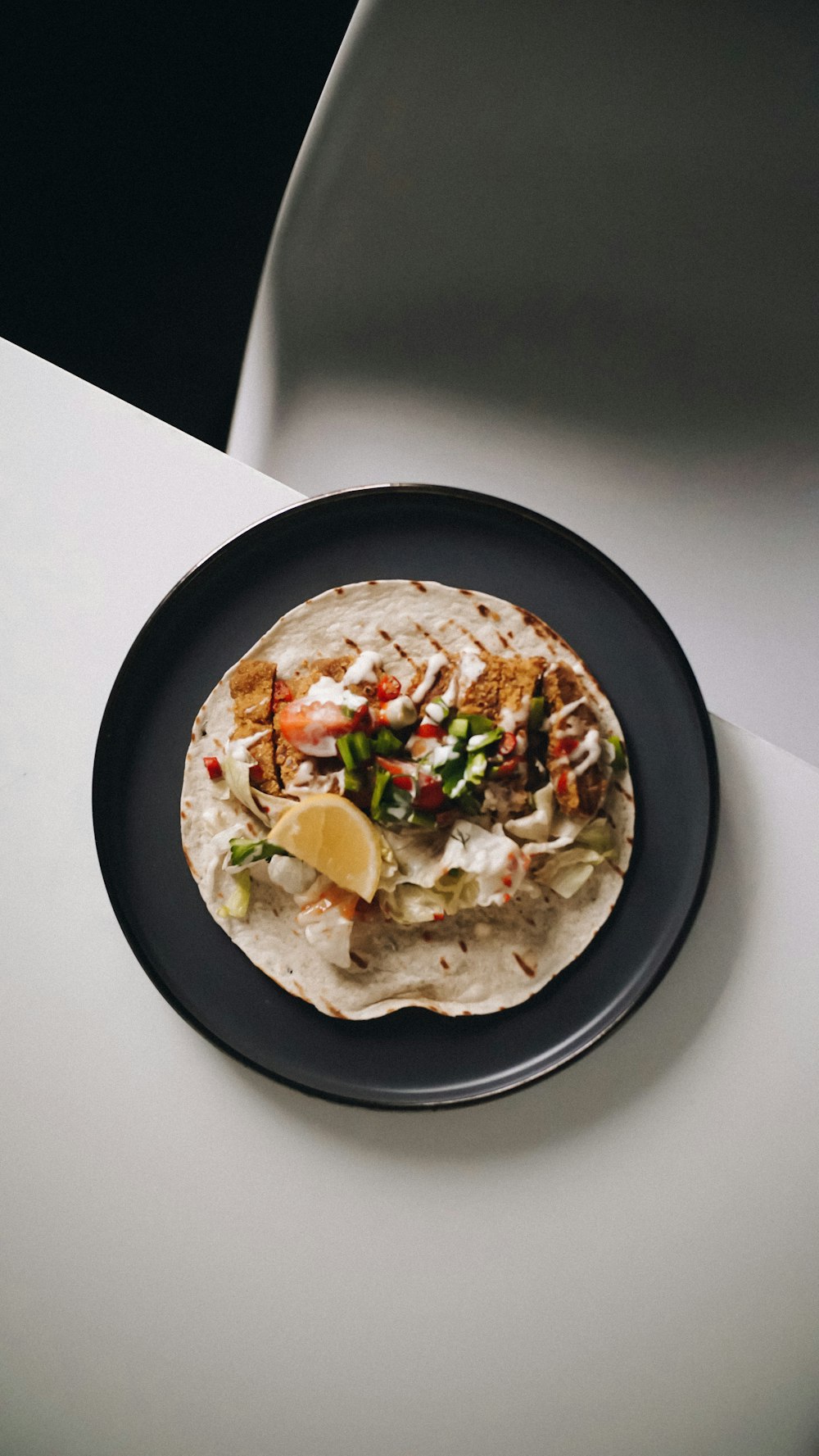 a black plate topped with a taco covered in toppings