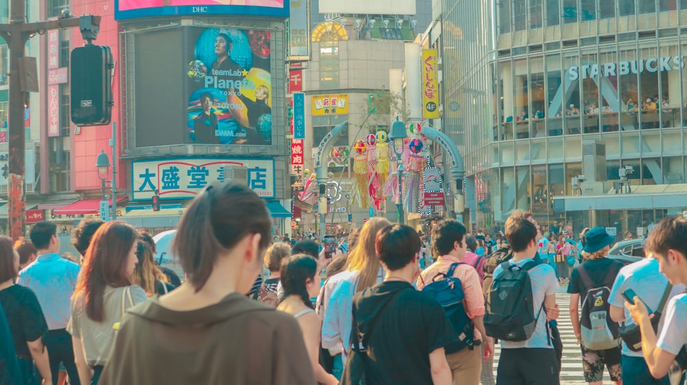 a crowd of people walking down a street next to tall buildings