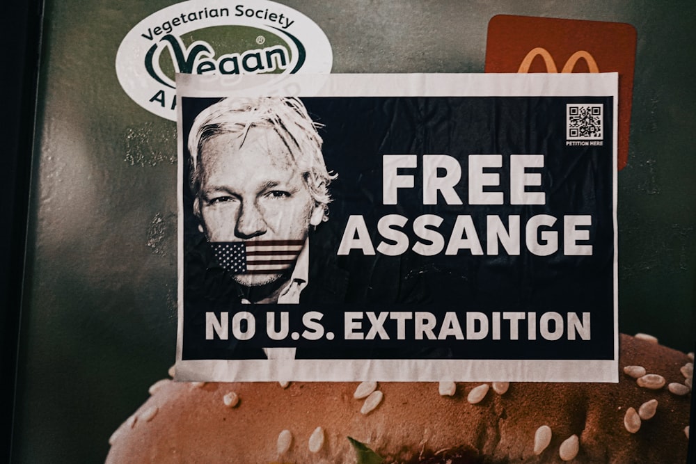 Una foto de una hamburguesa con un letrero de Assange gratis