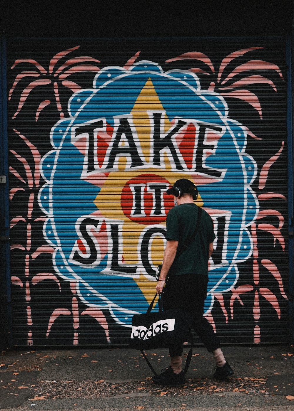 a man walking past a garage door with graffiti on it