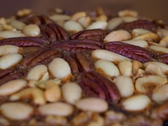 A close-up of peanuts and caramel being mixed into nougat.