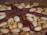 A close-up view of a baked treat featuring a dense layer of mixed nuts, including pecans and almonds, arranged decoratively on top.