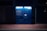 A blue Amazon parcel locker is illuminated against a dark background, featuring compartments and a screen for package retrieval. It displays phrases in Italian, suggesting its use for ordering and pickup.
