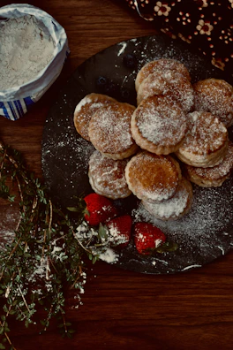 Delicate pastries topped with fresh fruit and a dusting of powdered sugar on a ceramic plate.
