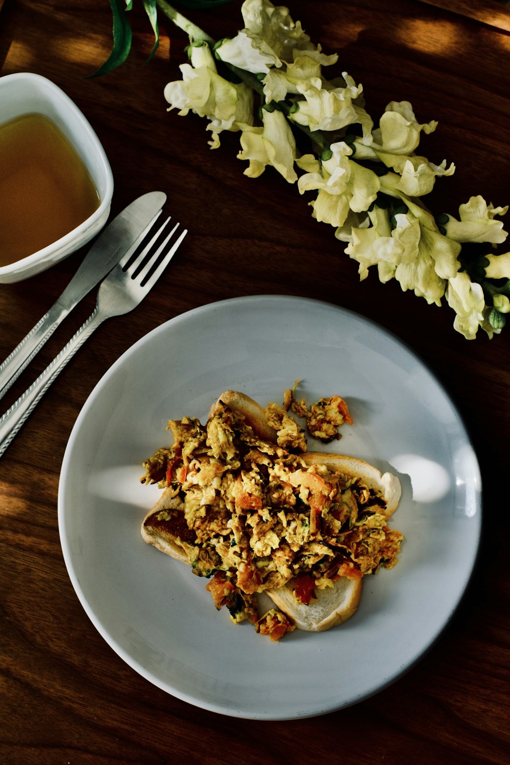 a white plate topped with food next to a cup of tea