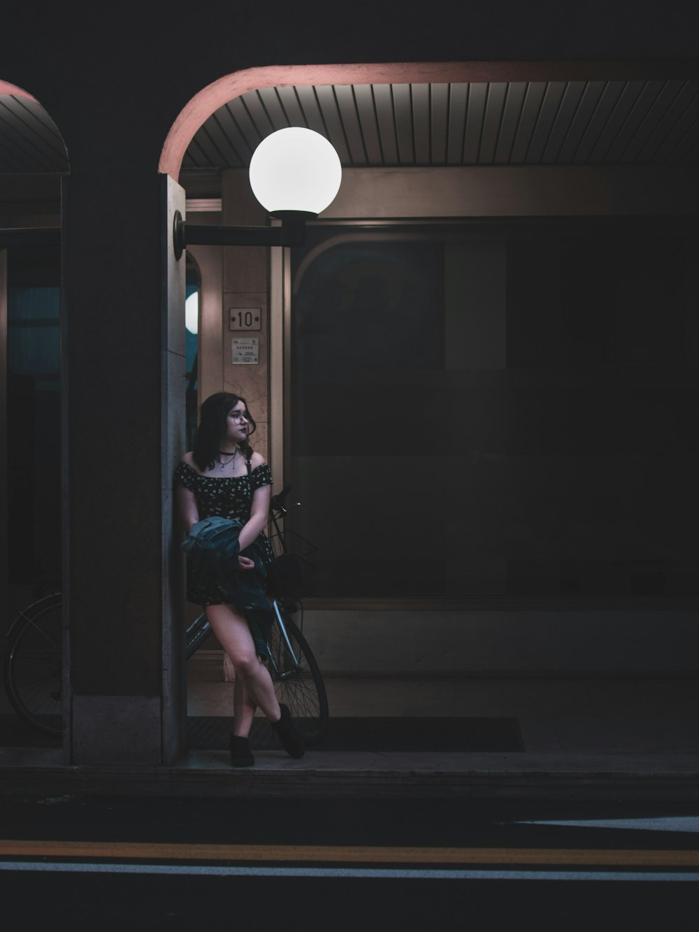 a woman standing on a sidewalk next to a bike