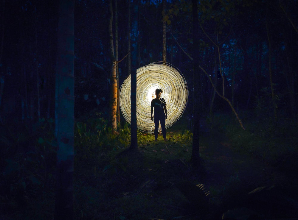 a person standing in the middle of a forest at night