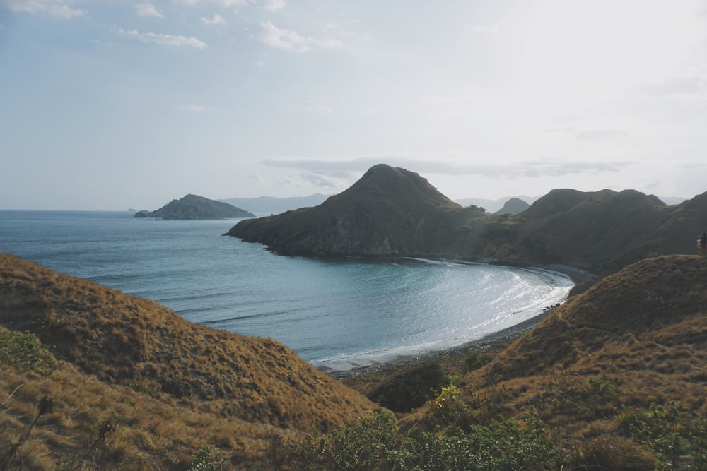 a body of water surrounded by hills and grass