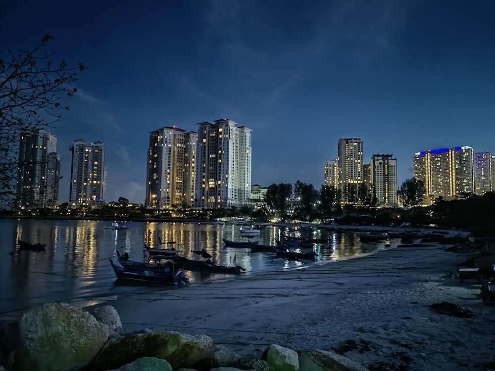 a group of boats floating on top of a river next to tall buildings