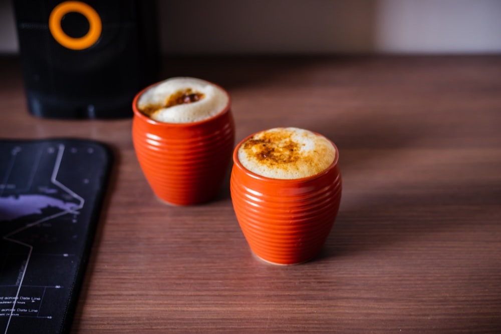 two orange cups sitting on top of a wooden table