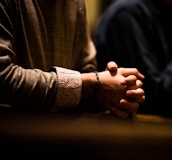 two people holding hands while sitting at a table