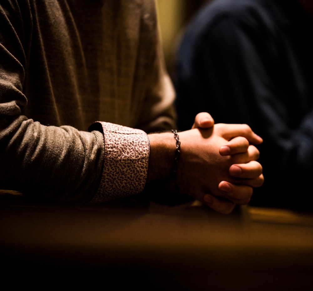 two people holding hands while sitting at a table