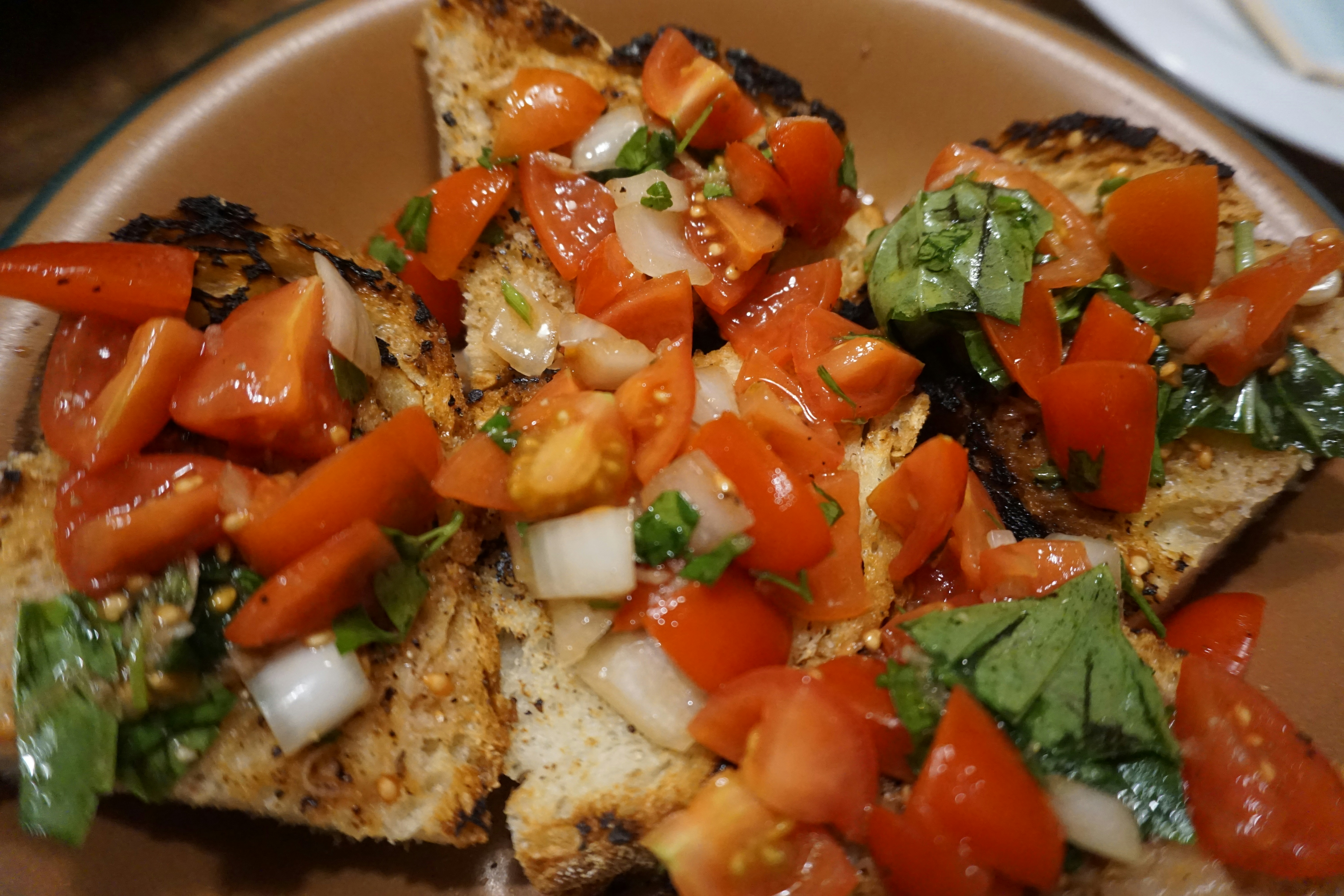 Bruschetta topped with diced tomatoes and fresh basil on toasted sourdough bread
