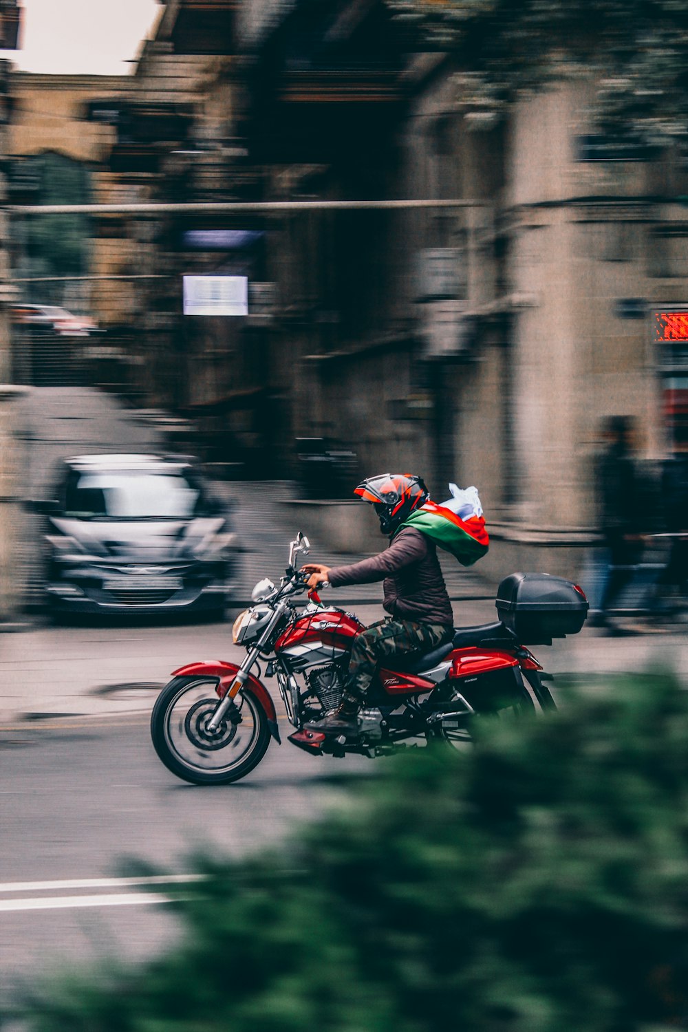 a man riding a red motorcycle down a street