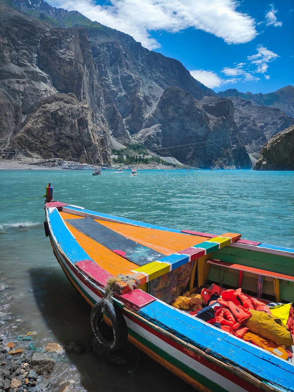 a colorful boat sitting on the shore of a lake