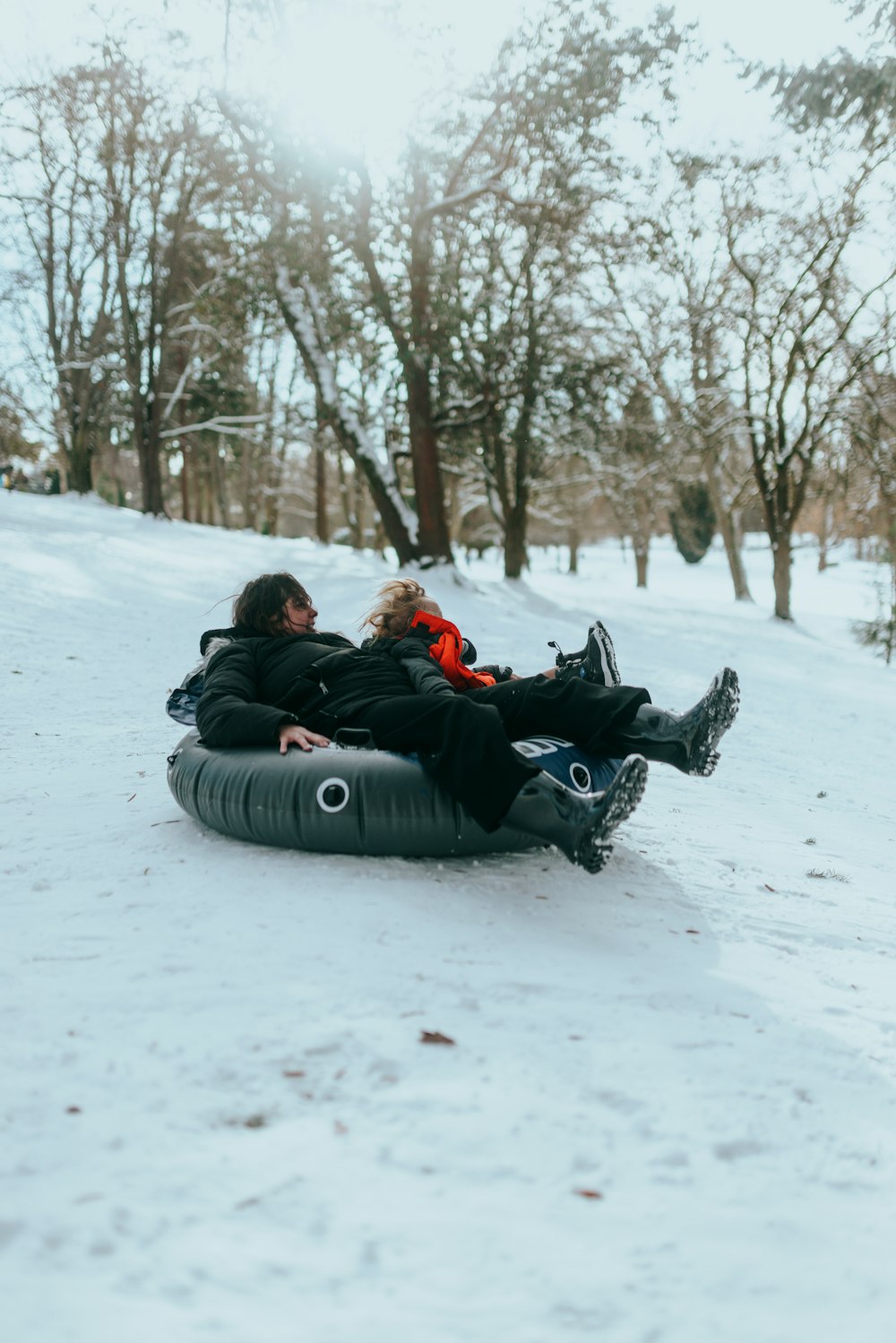 a man and a woman are sledding down a hill