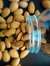 Close-up of fresh almonds pouring from a burlap sack onto a wooden surface.