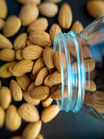Close-up of fresh almonds spilling from a rustic burlap sack onto a wooden table.