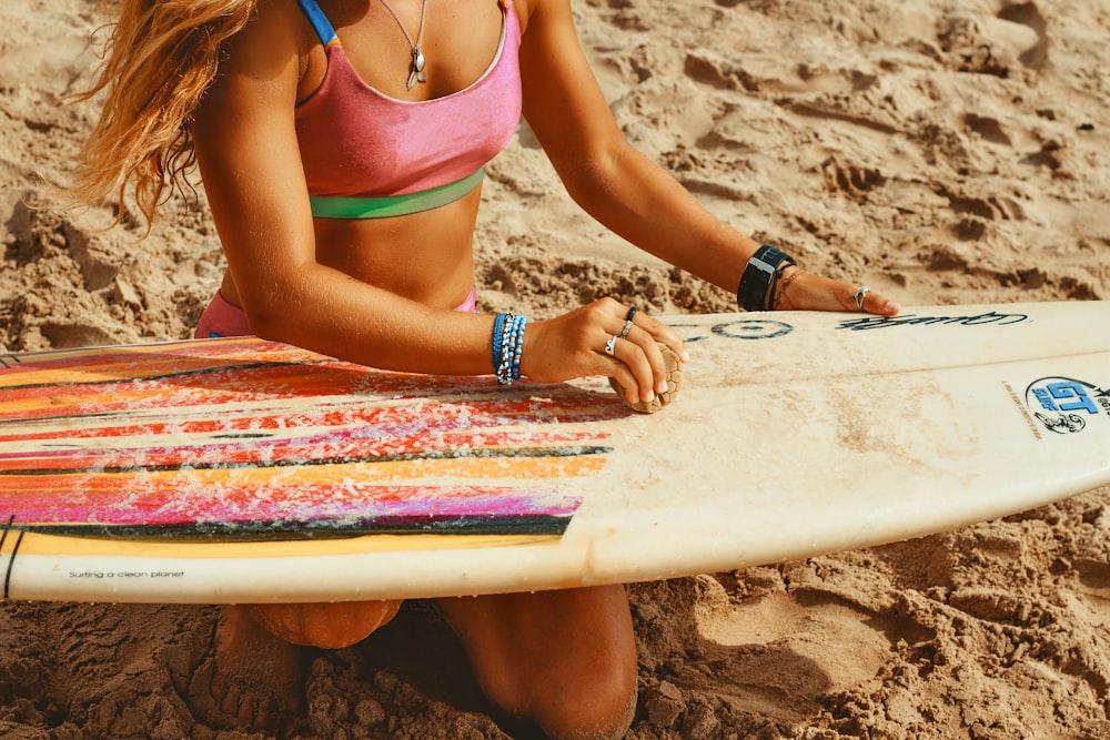 a woman sitting in the sand with a surfboard