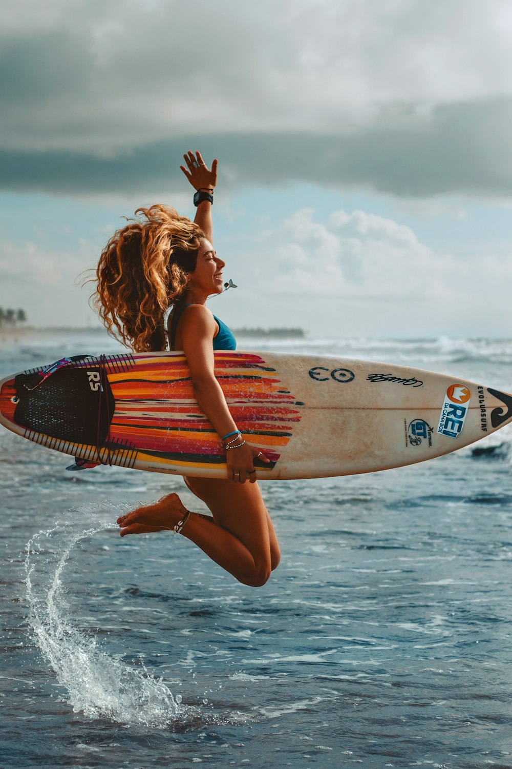 a woman jumping into the air while holding a surfboard