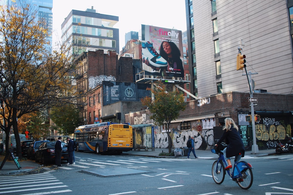 a woman riding a bike down a street next to tall buildings