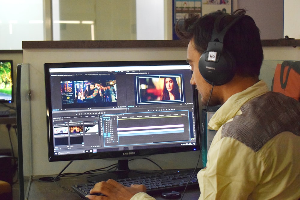 a man sitting in front of a computer with headphones on