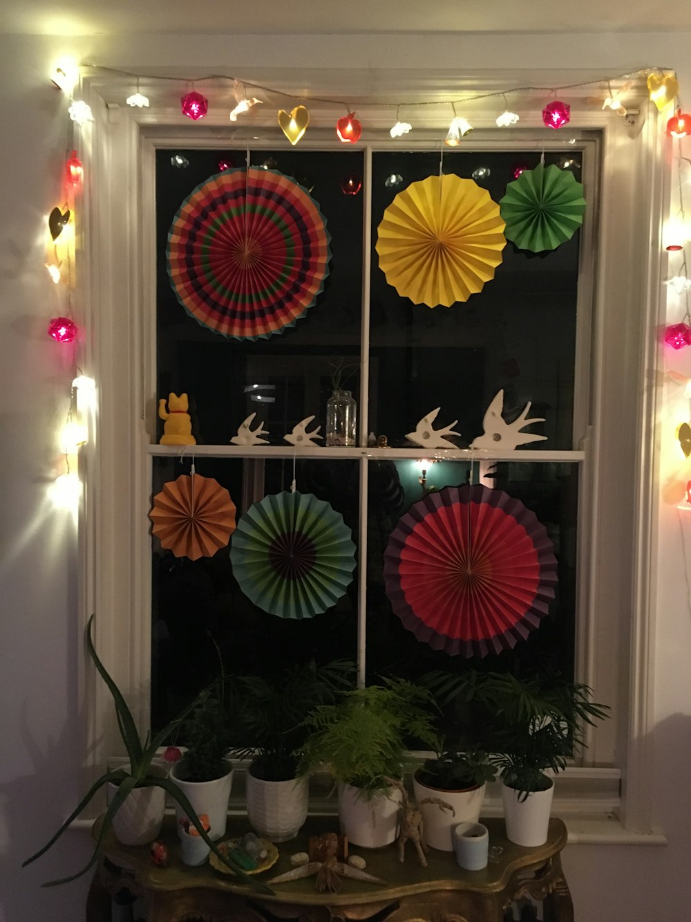 a window decorated with paper fans and potted plants