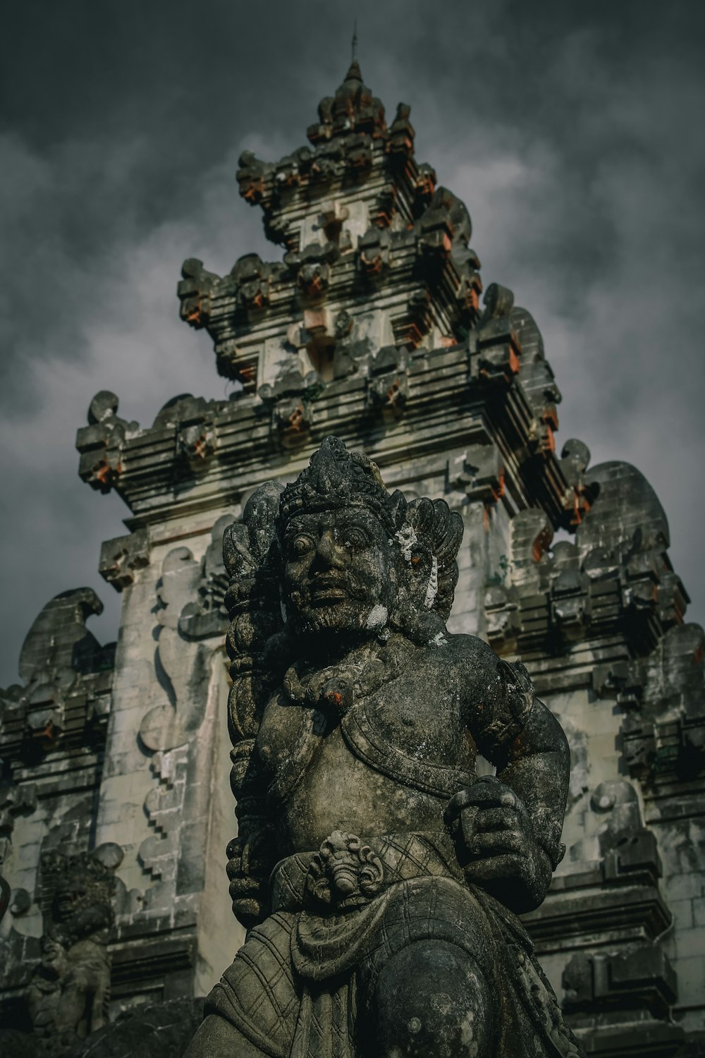 a statue of a god in front of a tall tower