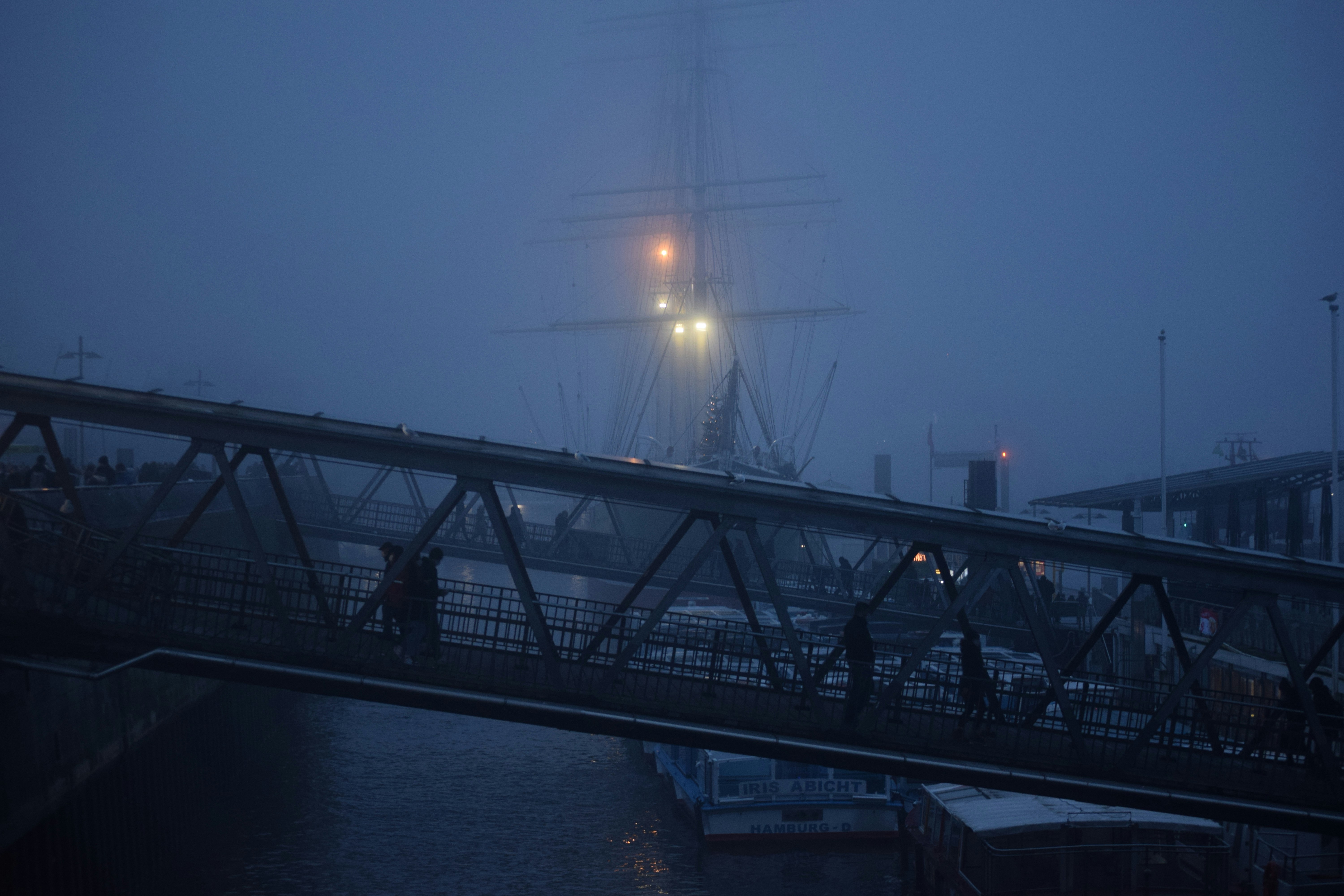 a foggy night in a harbor with a ship in the distance