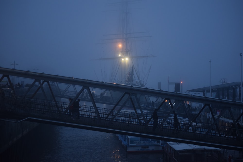 a foggy night in a harbor with a ship in the distance