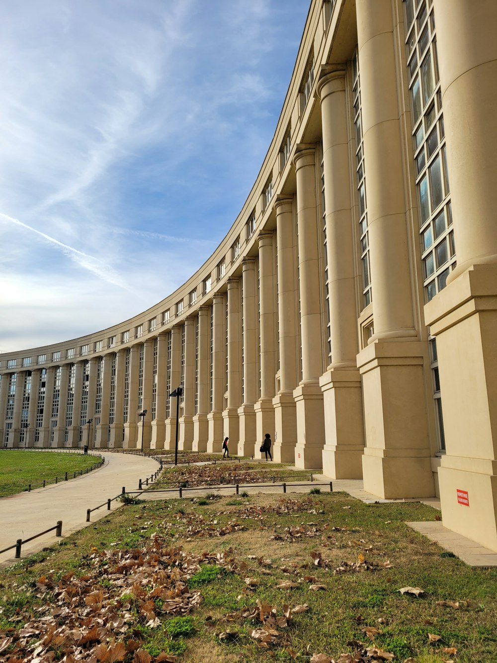 un grand bâtiment avec des colonnes et de l’herbe devant lui