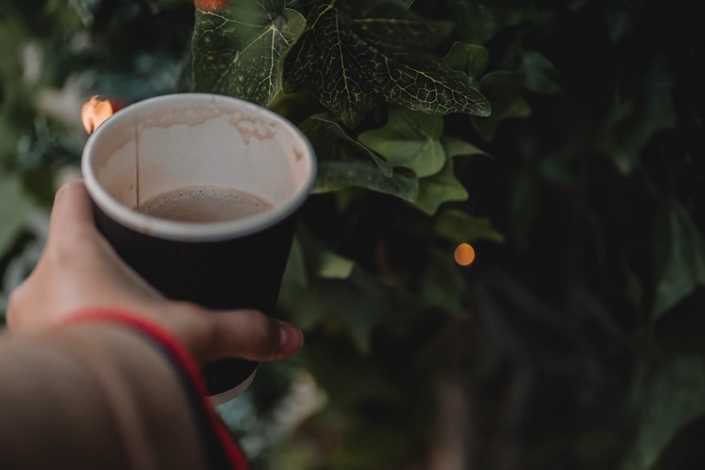 a person holding a cup of coffee in their hand