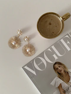 A cozy corner with a minimalist fashion outfit laid out next to a steaming cup of tea and a fashion magazine.