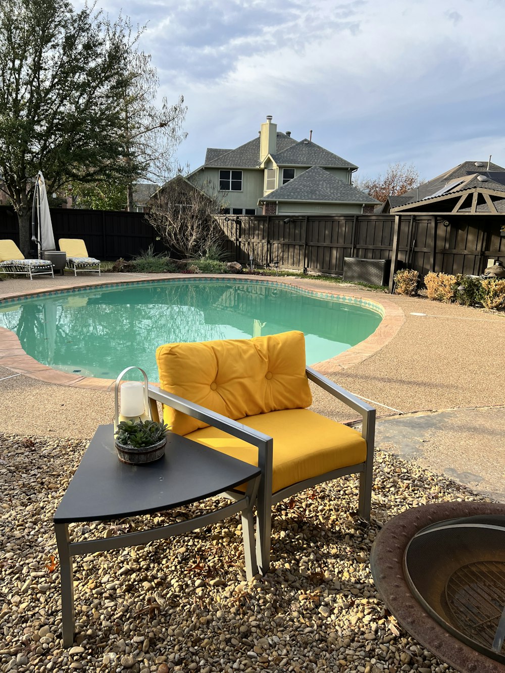 uma cadeira amarela sentada ao lado de uma piscina