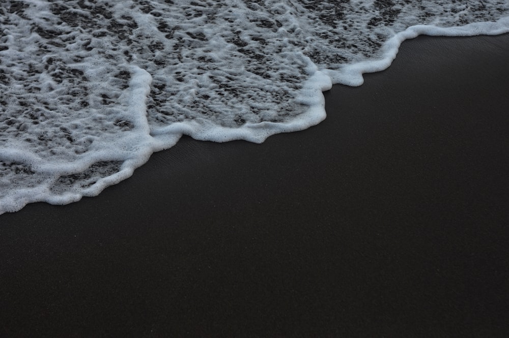 a black sand beach with white foamy waves