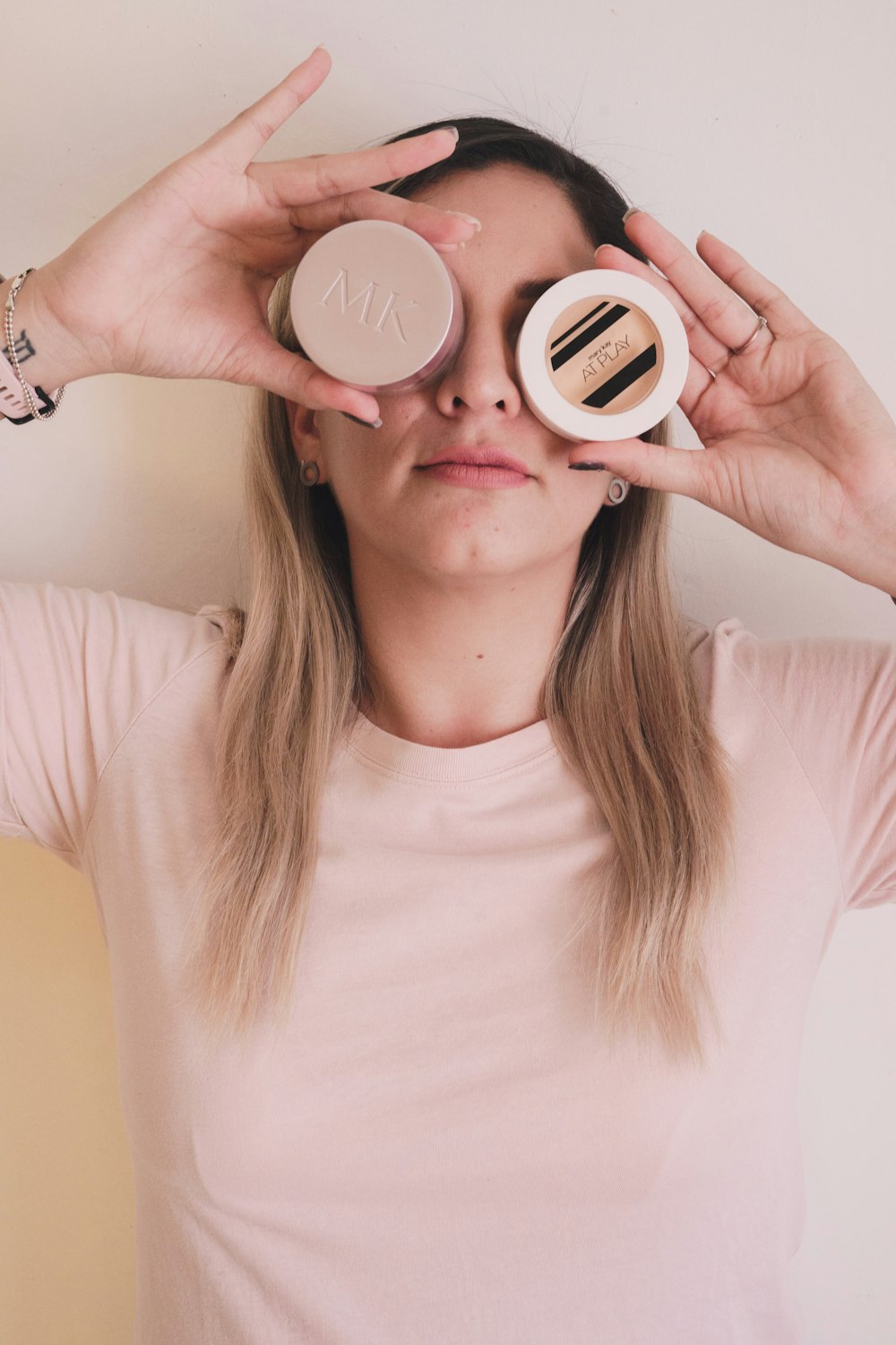 a woman looking through two jars of makeup