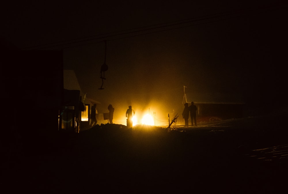 Un groupe de personnes debout autour d’un feu dans l’obscurité