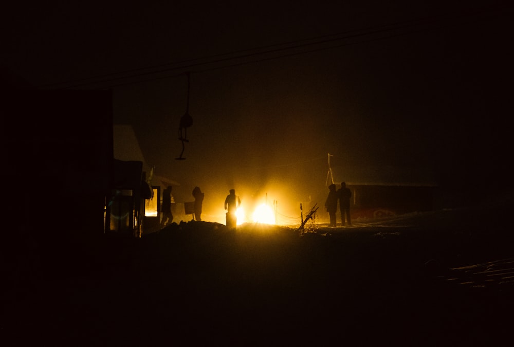 a group of people standing around a fire in the dark