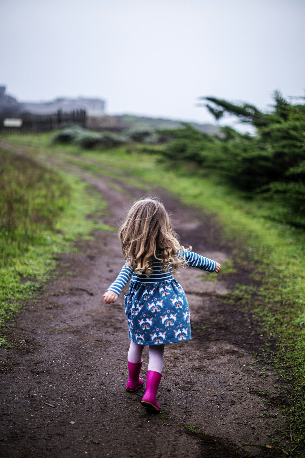 a little girl walking down a dirt road