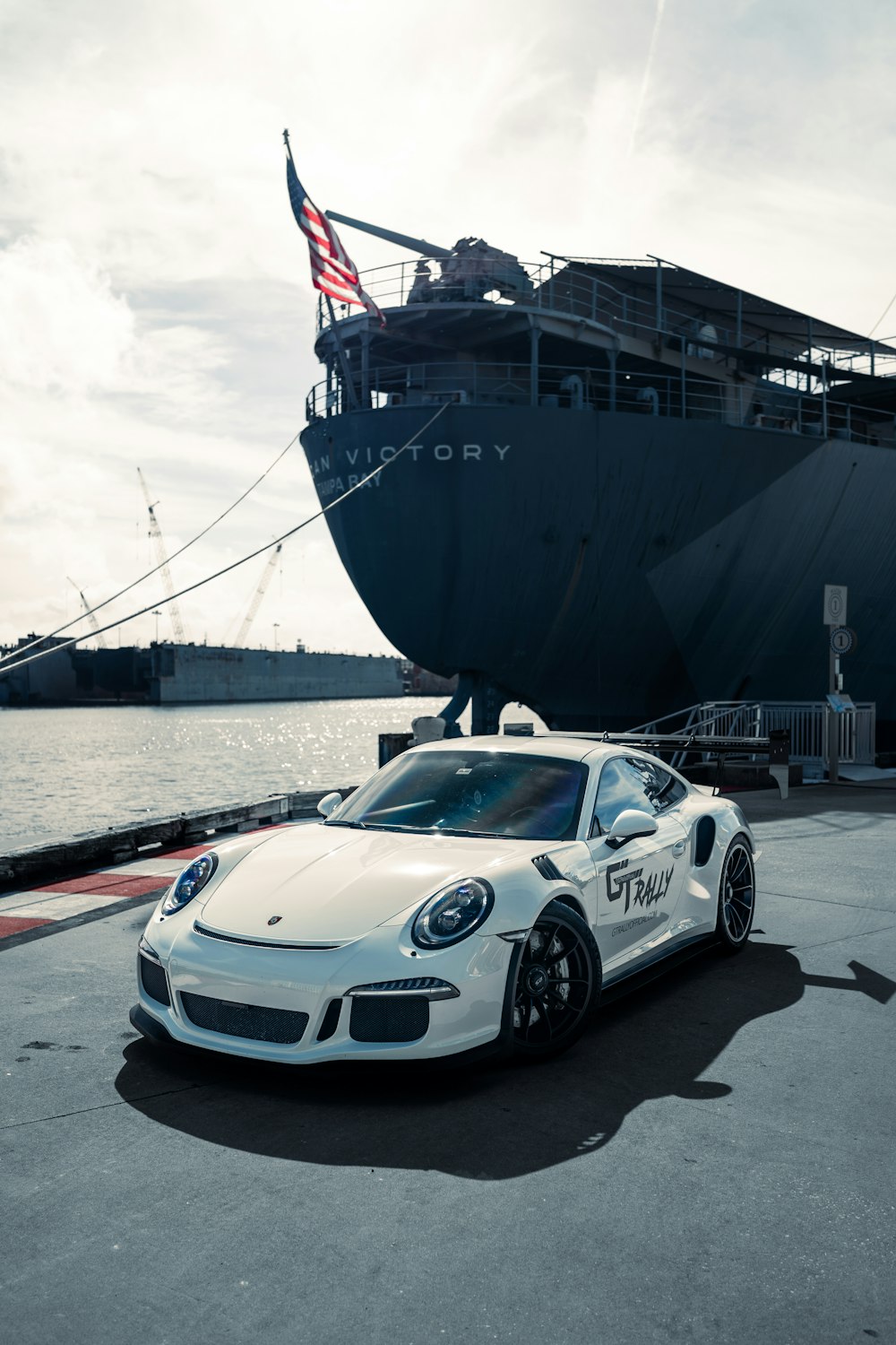 a white sports car parked in front of a large ship
