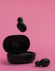 Stylish pink wireless earbuds resting on a matching charging case.