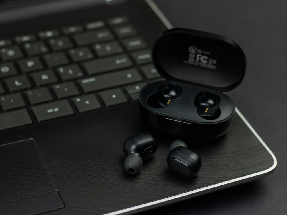 a pair of ear buds sitting on top of a laptop