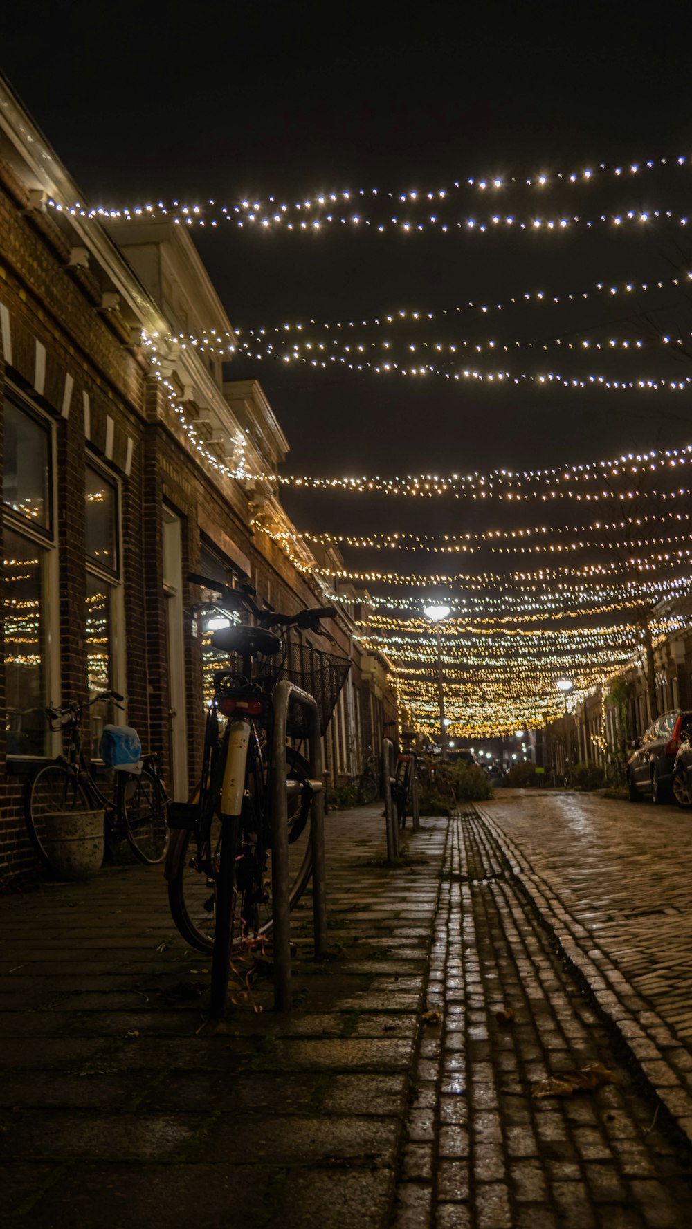a cobblestone street with lights strung overhead