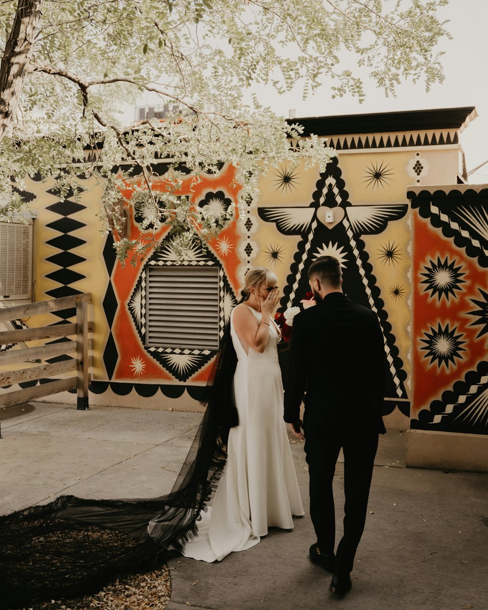 a bride and groom standing in front of a colorful wall